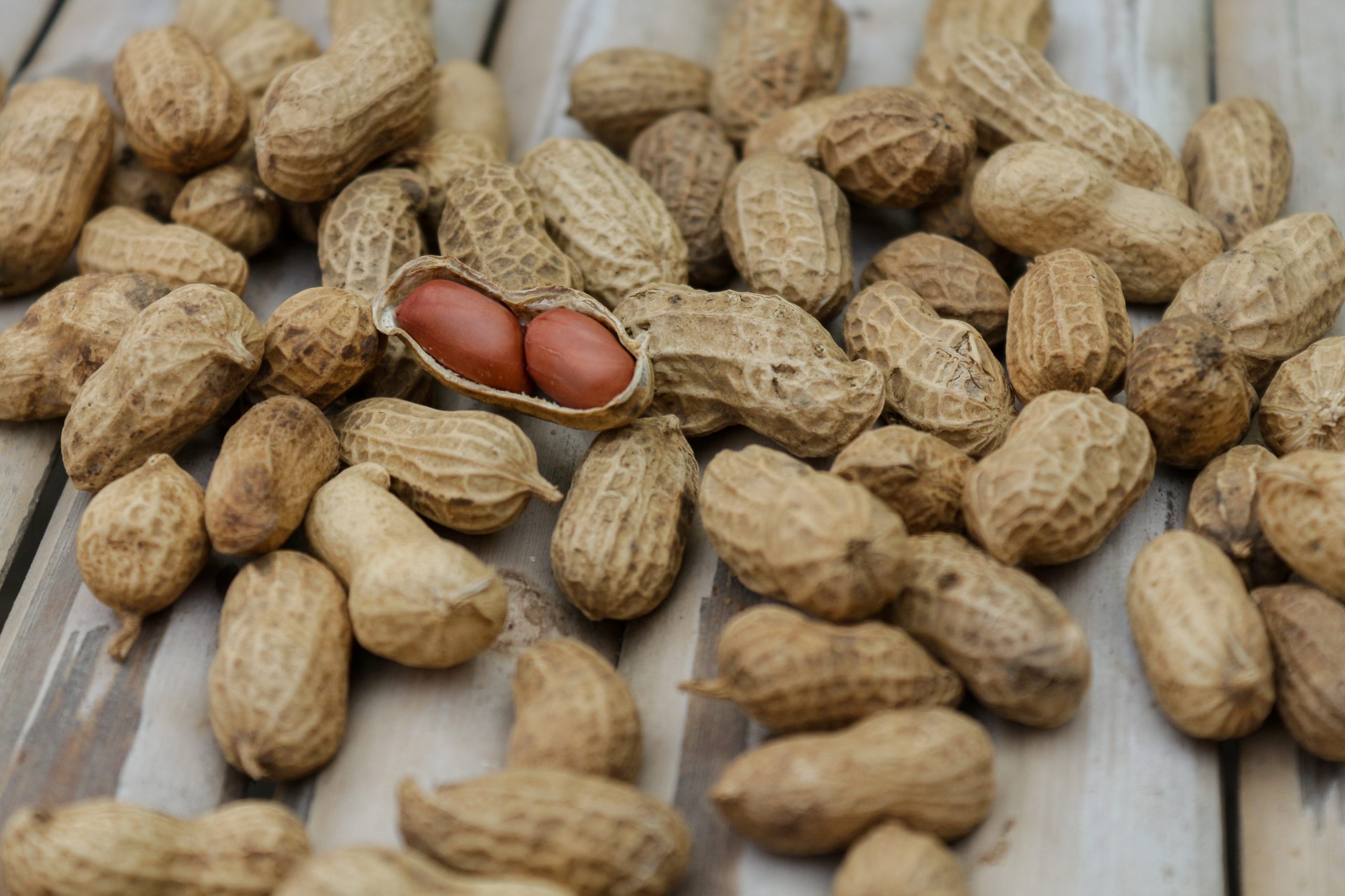 A detailed close-up of peanuts in their shells scattered on a wooden surface.